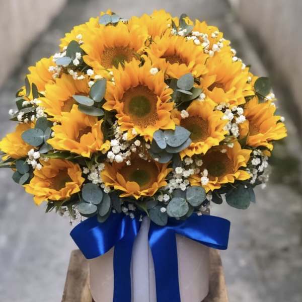 Bouquet of yellow sunflowers with blue ribbon in a white box