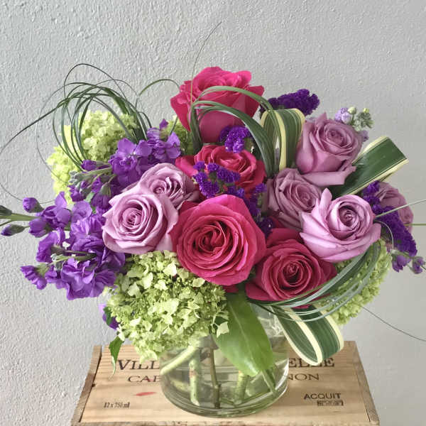 Bouquet of pink and lavender roses with purple flowers in a glass vase