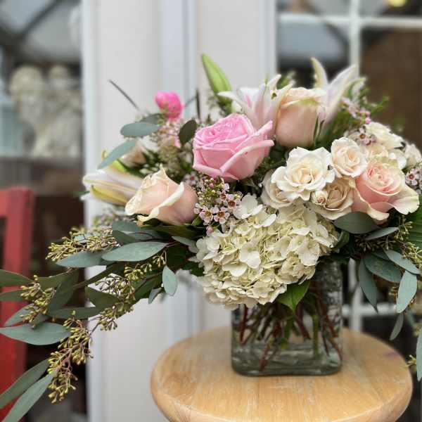 Pink and cream rose bouquet in a square glass vase