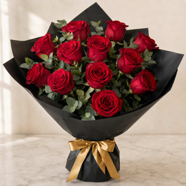 Bouquet of red roses wrapped in black paper with a gold ribbon