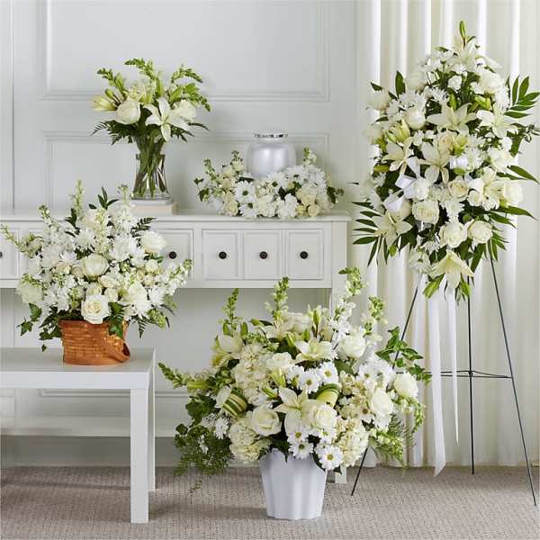 White floral funeral arrangements in vases and a standing spray