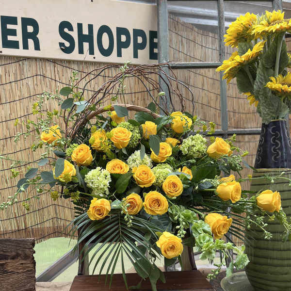 Yellow roses arranged with pale green blooms in a basket display