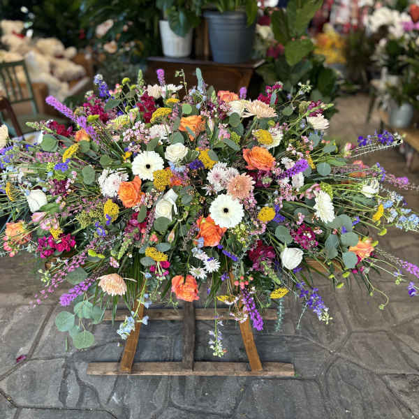 Large colorful floral spray on a wooden stand