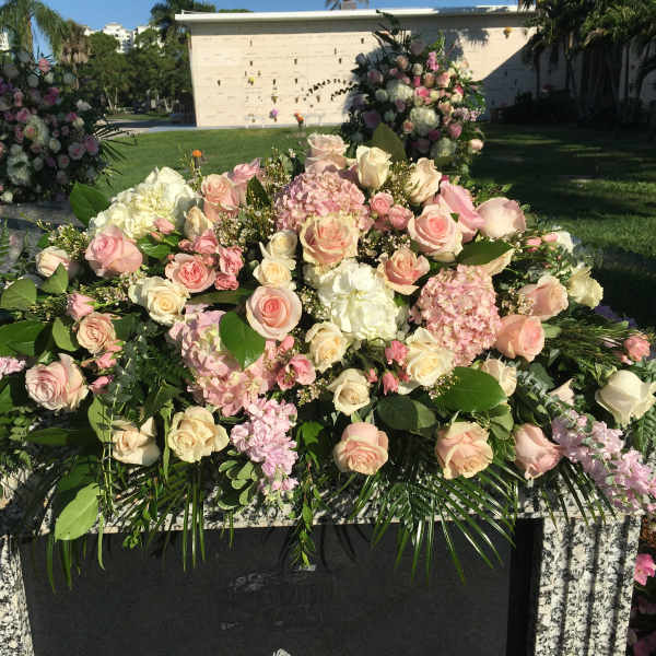 Large pink and white floral arrangement on a stone memorial