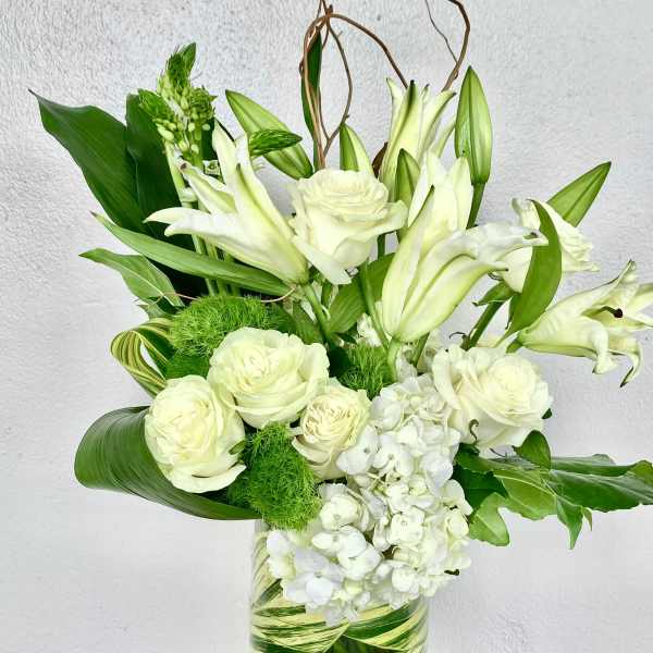 White roses and lilies arranged in a green-striped glass vase