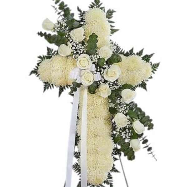 White floral standing cross with ribbon and greenery