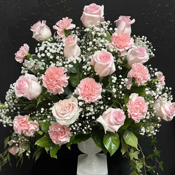 Pink roses and carnations arranged in a white pedestal vase