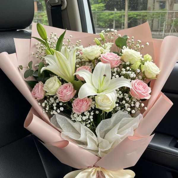 Pink and white bouquet with lilies and roses wrapped in blush paper