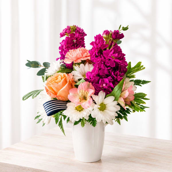 Mixed bouquet in a white vase with pink, peach, and white flowers