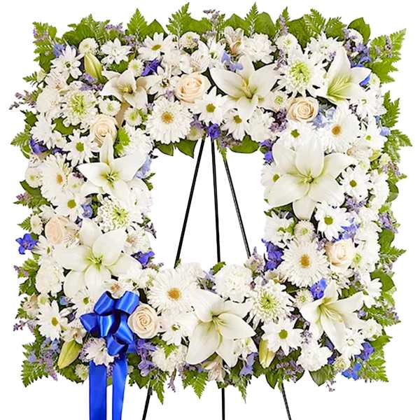 White floral standing wreath on an easel with a blue ribbon