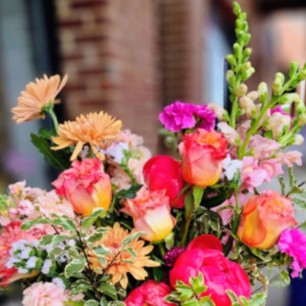 Mixed bouquet of pink and peach flowers in a white vase