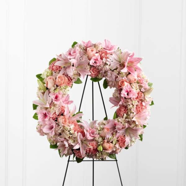Pink floral wreath on a black stand