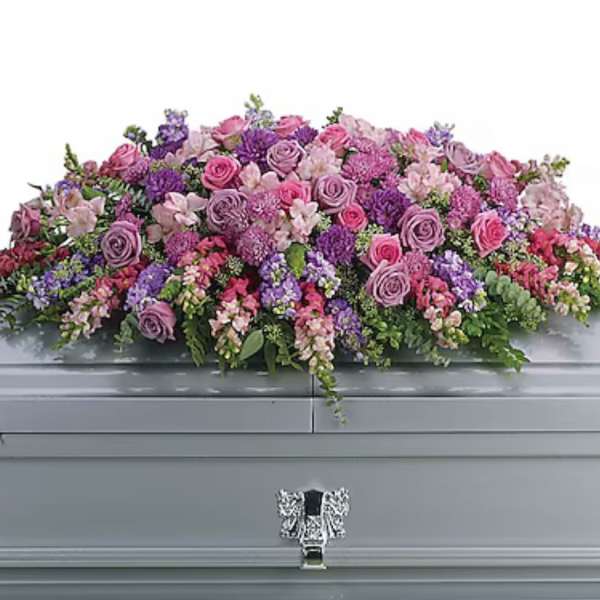 Large pink and purple floral casket spray on a gray casket