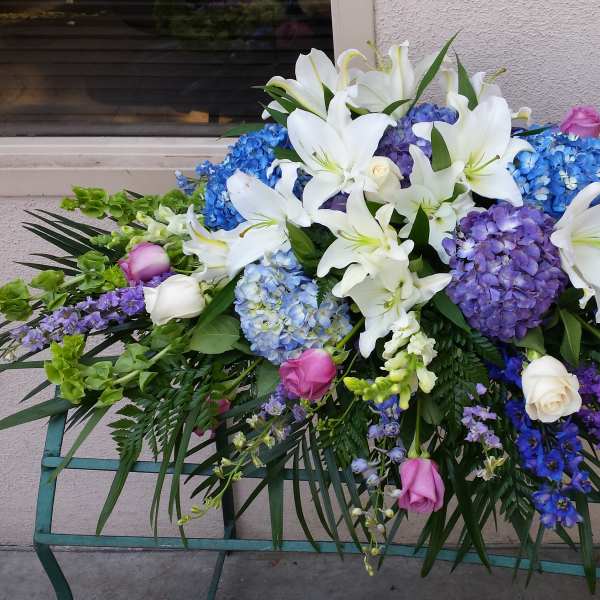 Large floral spray with white lilies, blue hydrangeas, and pink roses