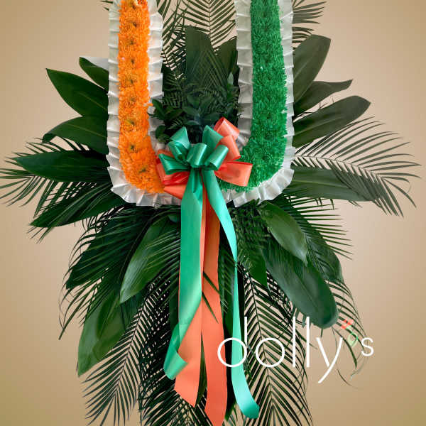 Large standing floral tribute with orange and green garlands and ribbon bow