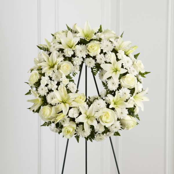 White floral wreath on a black easel stand