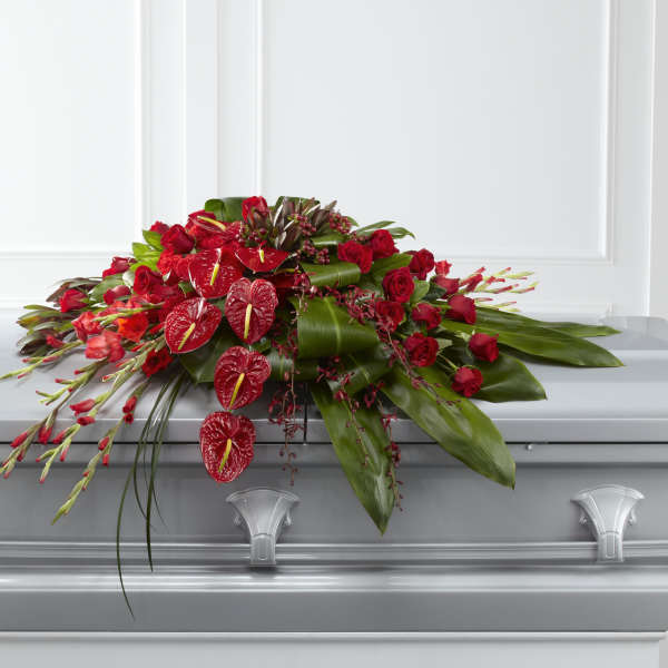 Red floral casket spray with roses and anthuriums
