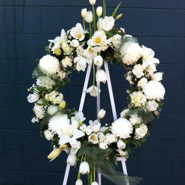 White floral wreath on a standing easel with trailing tulips