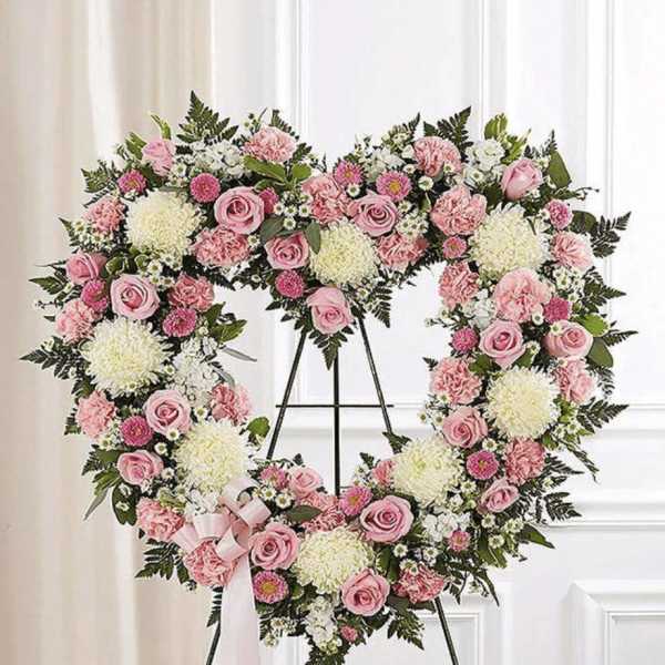 Heart-shaped floral wreath of pink and white flowers on a stand