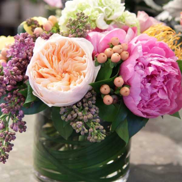 Mixed bouquet of pink, peach, and white flowers in a glass vase
