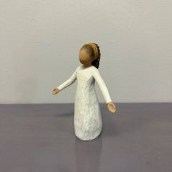 Small carved figurine of a person in a white dress