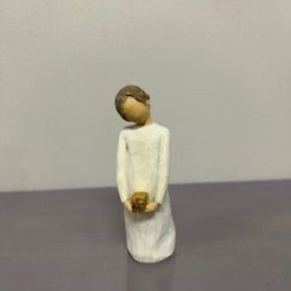 Small figurine of a person in a white dress holding a tiny object