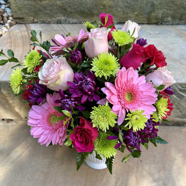Mixed pink, purple, and green bouquet in a white vase