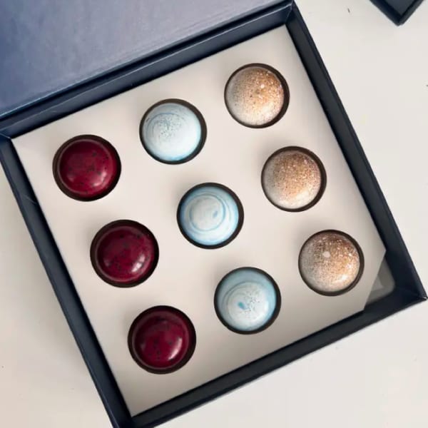Box of assorted round chocolates in red, blue, and gold