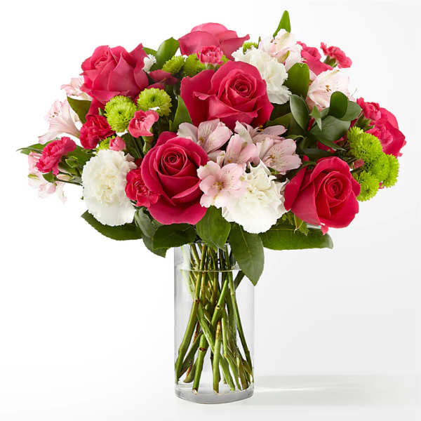 Bouquet of pink roses, white carnations, and green pompons in a clear glass vase