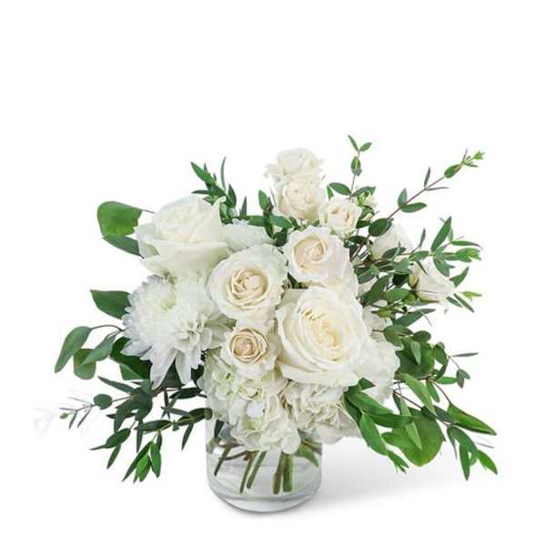 White roses and mums in a clear glass vase with greenery