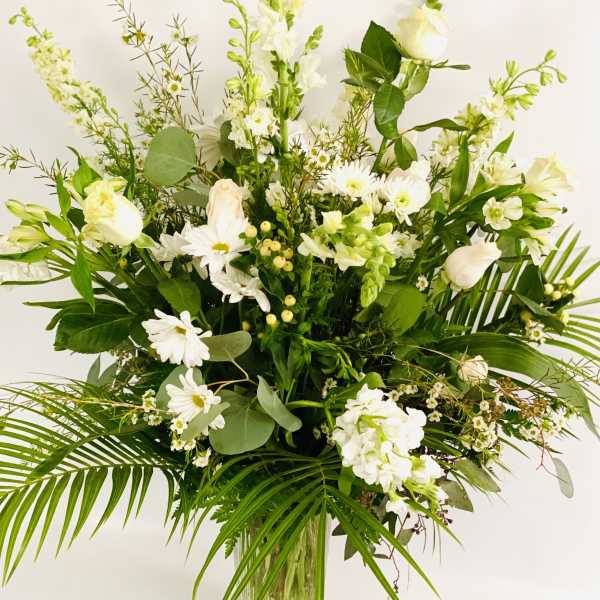 Tall white floral arrangement in a clear glass vase