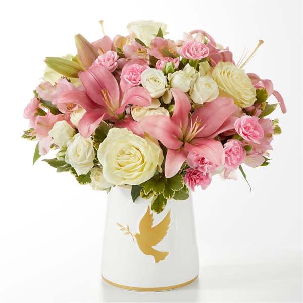Pink and white flower bouquet in a white vase with a gold dove design