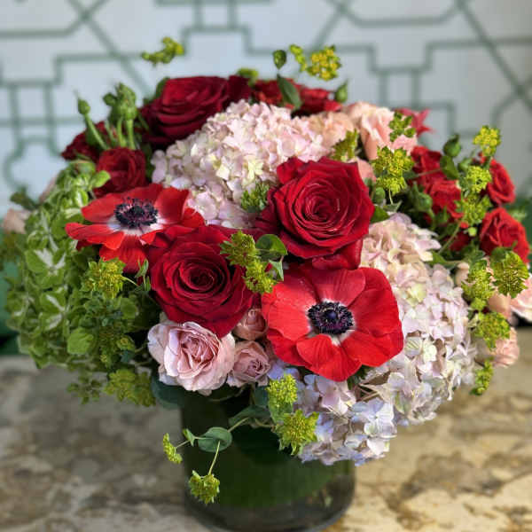 Red roses and pale hydrangeas arranged in a dark vase