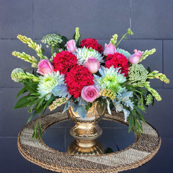 Mixed bouquet in a gold vase with pink roses and red carnations