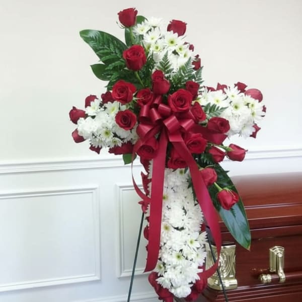 Standing funeral spray of red roses and white daisies with a ribbon