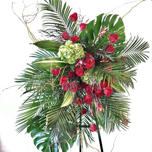 Tall tropical arrangement with red roses and large palm leaves