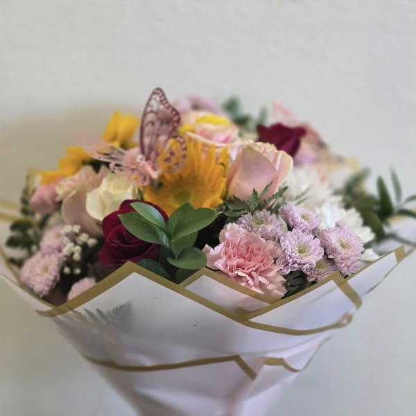 Bouquet of pink, white, and yellow flowers wrapped in white paper