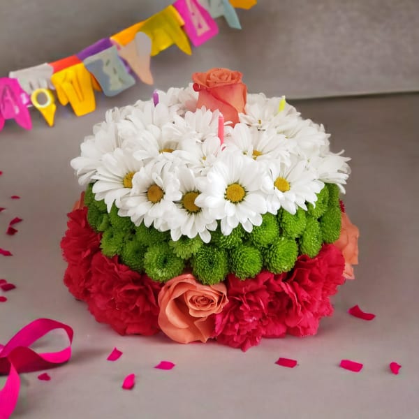 Round floral cake with white daisies, green mums, and pink roses