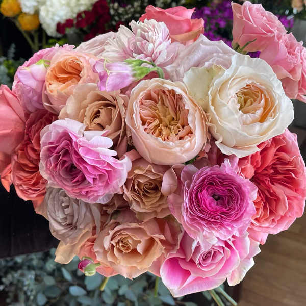 Hand-tied bouquet of pink, peach, and cream roses and ranunculus.