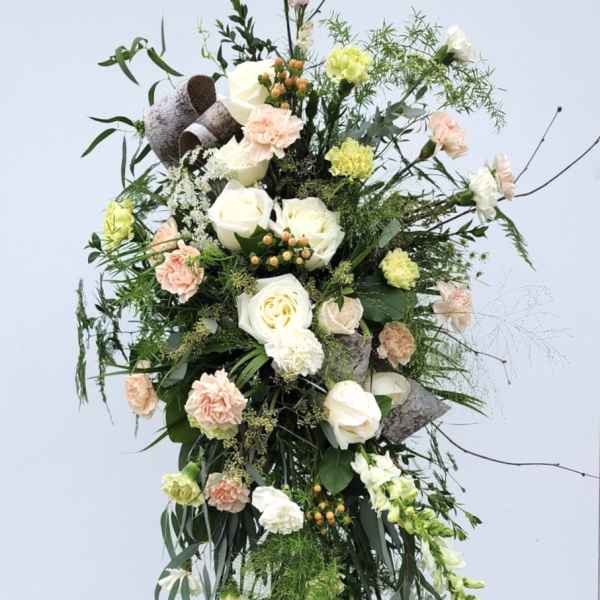 Tall floral standing spray with white and peach blooms on a metal easel