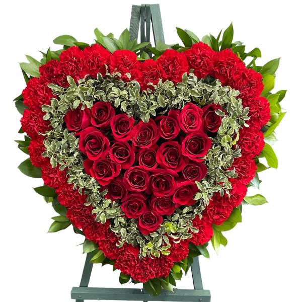 Heart-shaped red rose and carnation wreath on an easel