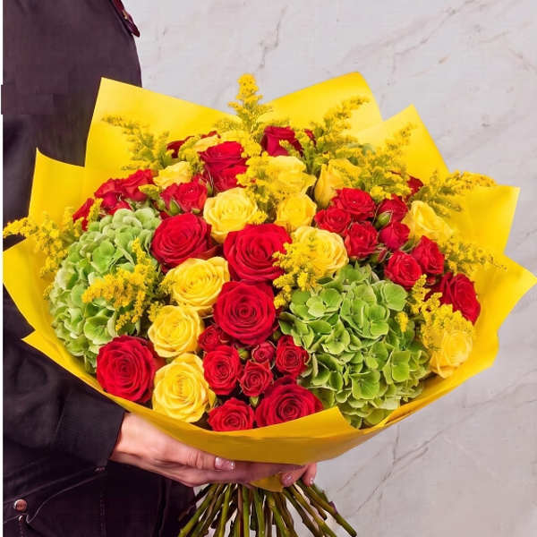 Bouquet of red and yellow roses with green hydrangeas in yellow wrap