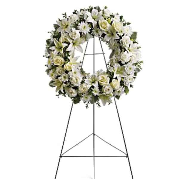 Standing wreath of white lilies, roses, and mums on a metal easel