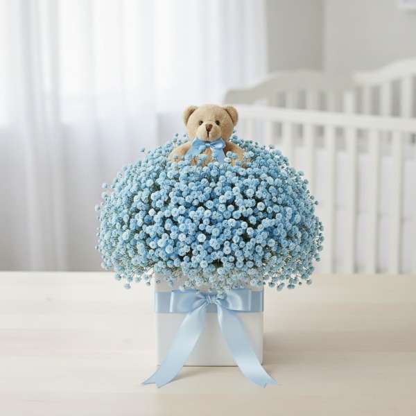 Blue baby's breath arrangement with a teddy bear topper in a white box
