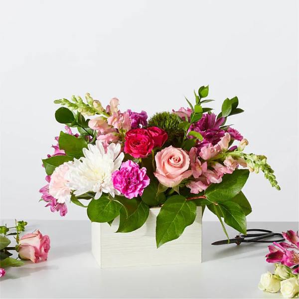 Mixed pink and white flower arrangement in a white box
