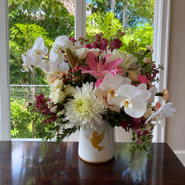Mixed floral arrangement in a white vase with orchids, lilies, and chrysanthemums