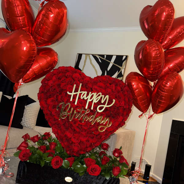 Heart-shaped rose arrangement with red balloons and a Happy Birthday sign