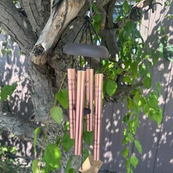 Rose-gold wind chime hanging from a tree branch