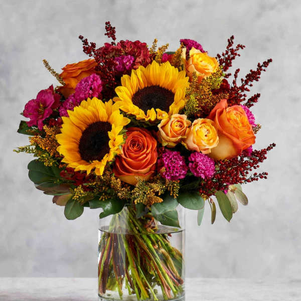 Bouquet of sunflowers and orange roses in a clear glass vase