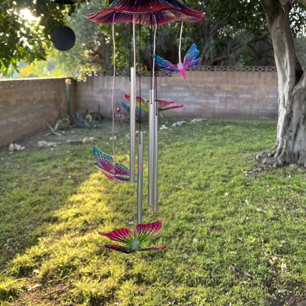 Colorful butterfly wind chime hanging outdoors in a yard